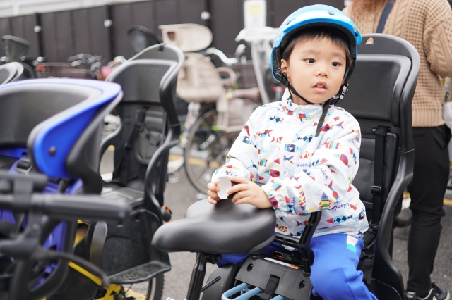 自転車の後方にある幼児シートに乗っている男の子