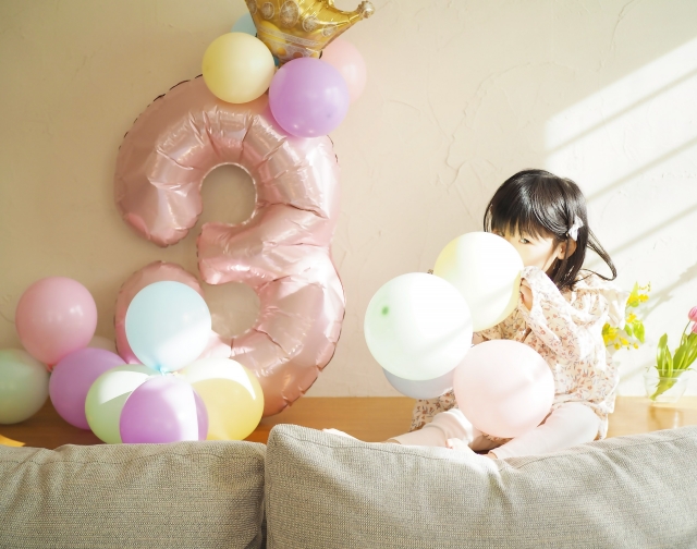 3歳のお誕生日を祝う風船の飾り付けをする女の子