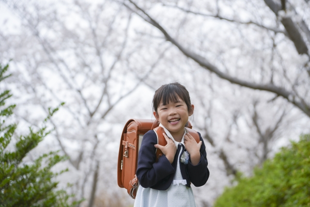 桜の木の下でランドセルを背負って嬉しそうにしている女の子