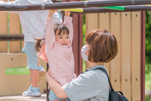 お母さんと雲梯をして遊ぶ子供