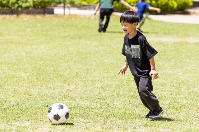 外でサッカーをして遊ぶ男の子