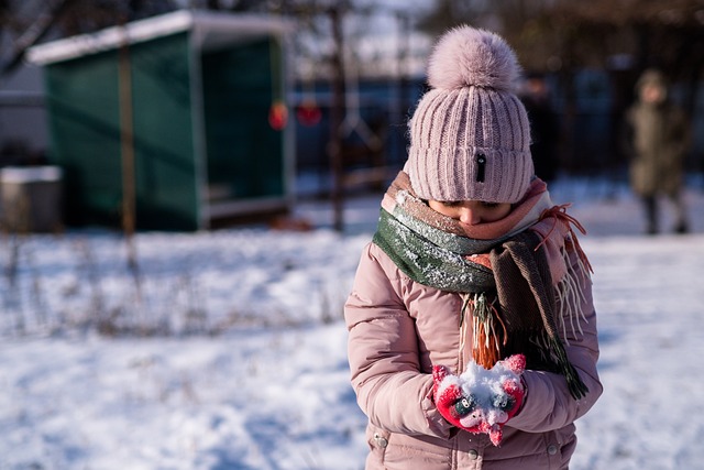 ピンク色のダウンジャケットを着た女の子が雪を持っている