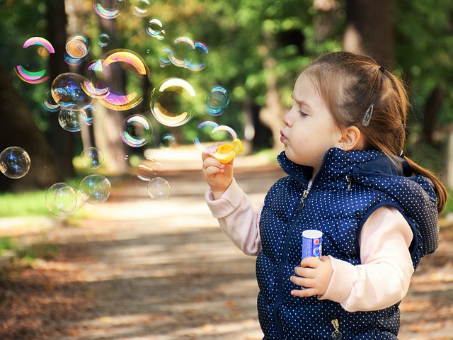 ダウンベストを着て公園でシャボン玉をしている女の子