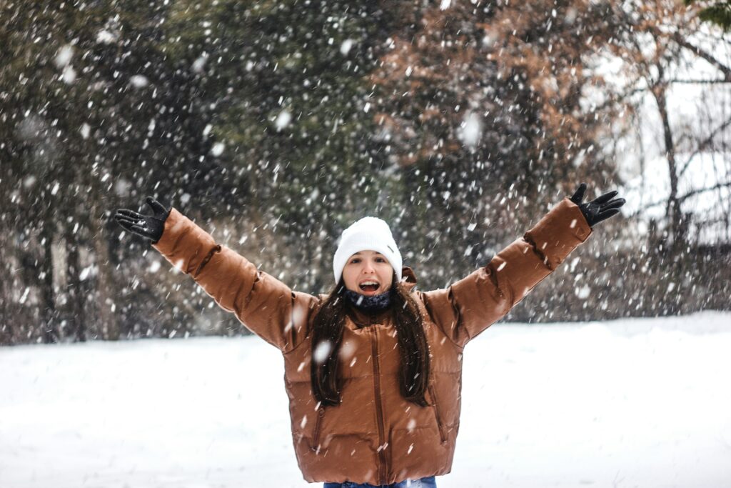 雪の中でバンザイする女性