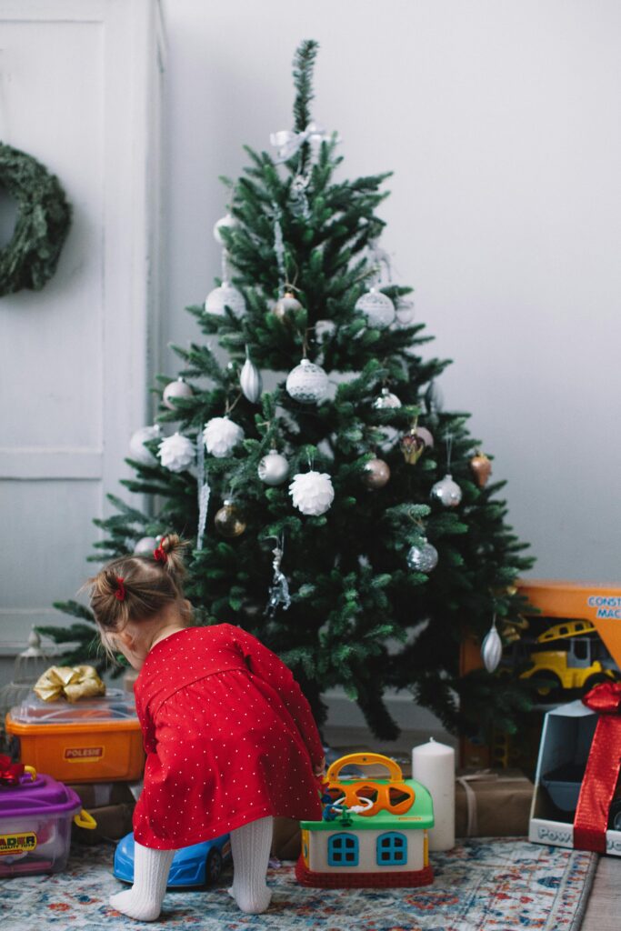 クリスマスツリーの前で遊ぶ赤いワンピースを着た女の子