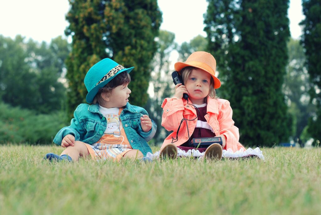 受話器を持った小さい子どもが2人で並んで座っている様子