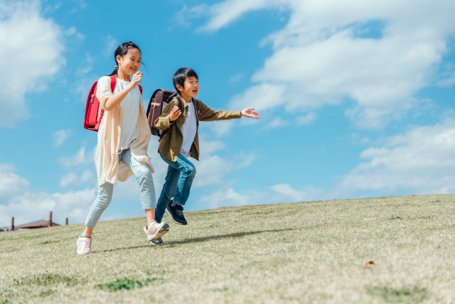 公園を走る小学生の女の子と男の子