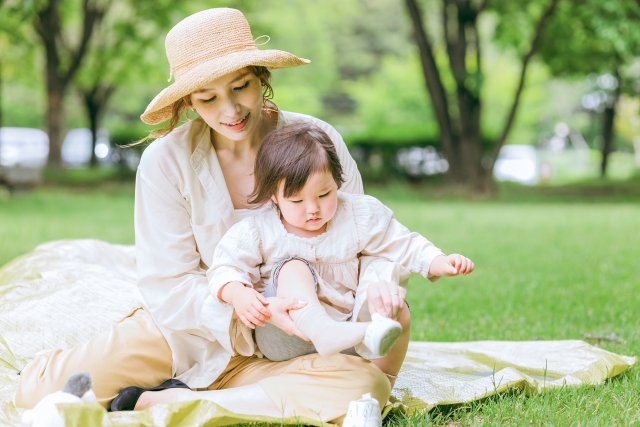 ママが膝の上に座らせている子どもに靴を履かせる様子