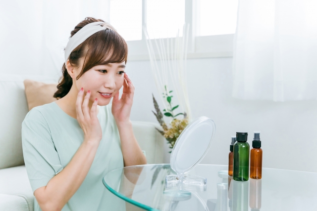 鏡を見て肌を保湿する女性