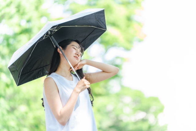 日傘を差しながらも暑がる女性