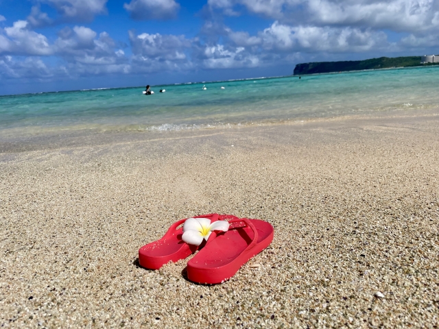 綺麗な海と青空と、砂浜にある赤いサンダル