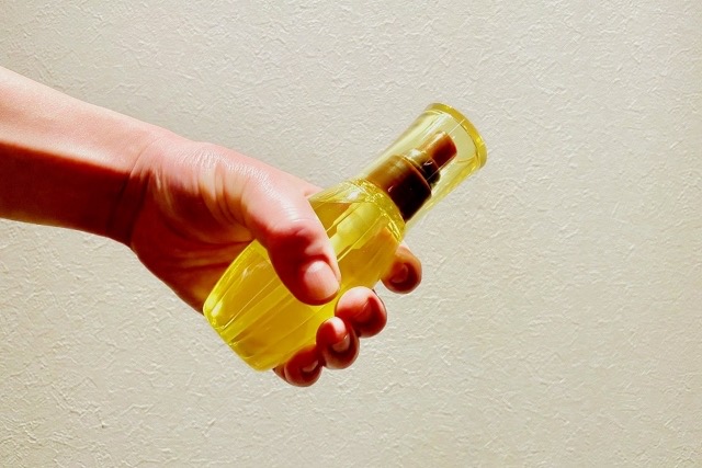 黄色のヘアオイルを手で持っている