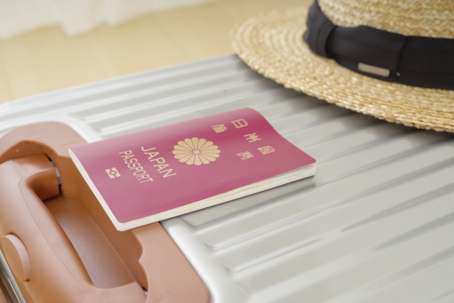パスポートとキャリーケースと麦わら帽子の旅行グッズ