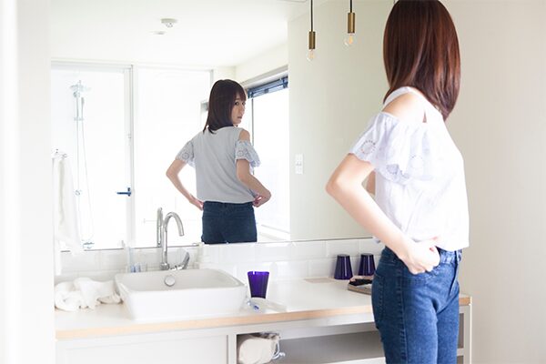 鏡でコーディネートを確認する女性