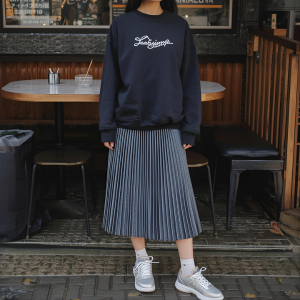 スウェットにグレーのプリーツスカートとシルバーのスニーカーを履いた女性