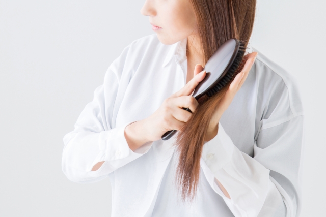 ヘアブラシで髪をとかす女性