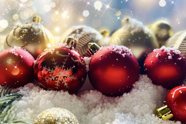 雪の上に置いてあるキラキラとした赤色とゴールドのクリスマスツリーオーナメント