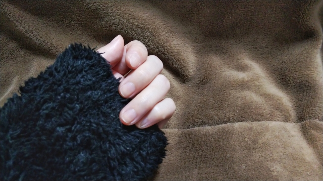 茶色のボア背景と黒いコートの手