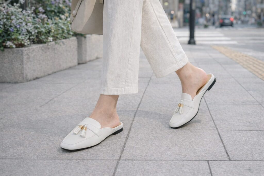 白いローファーミュールで歩く女性